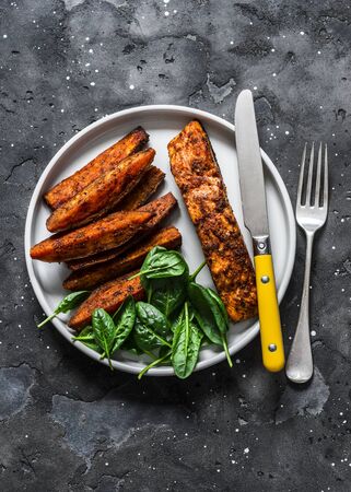 Crispy spice crust baked salmon with sweet potato and spinach - healthy balanced lunch on dark background, top viewの写真素材