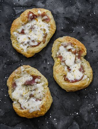 Puff pastry, ham, mozzarella cheese breakfast pizza on a dark background, top viewの写真素材