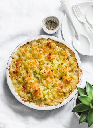 Creamy chicken, cauliflower, leek pie with crispy potato cheese topping on light background, top view. Comfort foodの写真素材