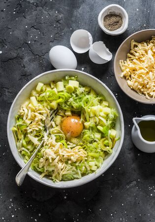 Ingredients for cooking leeks, zucchini, potato frittata on a dark background, top viewの写真素材