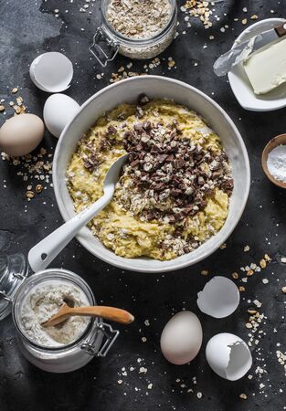 Cooking banana oatmeal cake with white and milk chocolate. Ingredients for the cake on a dark background, top view. Flat layの写真素材
