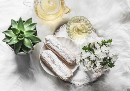 Green tea, eclairs, teapot and chrysanthemum flowers on a light background, top viewの写真素材