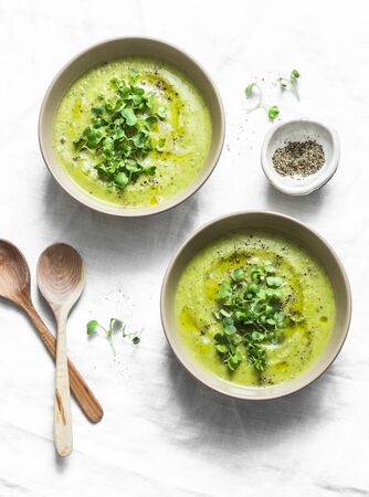 Mashed broccoli soup served with micro greens on a light background, top view. Healthy vegetarian food conceptの写真素材