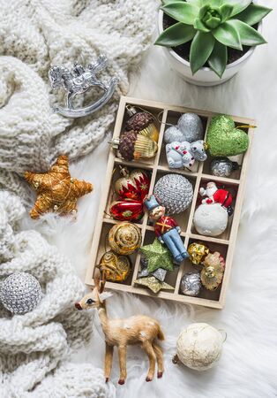 Coziness christmas still life. Knitted plaid, box of christmas toys, succulent flower on cozy fluffy carpet, top view. Christmas backgroundの写真素材