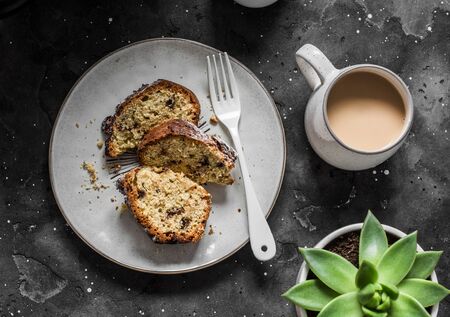 White and milk chocolate banana oatmeal cake, coffee, succulent flower on a dark table background, top view. Delicious breakfast, snack, dessertの写真素材