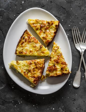 Slice of leeks, potatoes, zucchini tortilla on a dark background, top view. Delicious appetizer, tapas, breakfastの写真素材