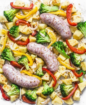 Comfort autumn winter lunch - turkey sausages, potatoes, broccoli, sweet peppers, onion, spices on a baking sheet, top viewの写真素材