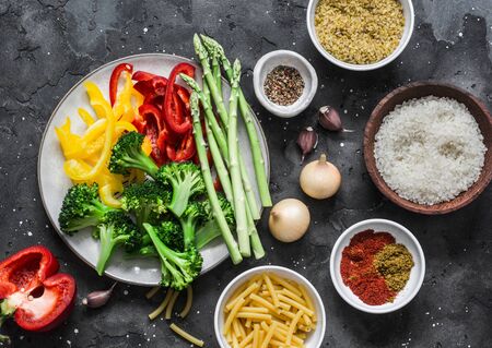 Set of products for vegetarian lunches - pasta, rice, bulgur and fresh vegetables on a dark background, top viewの写真素材