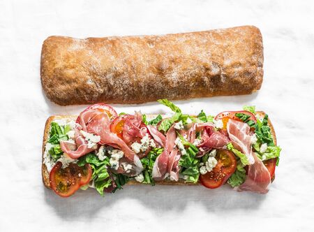 Bruschetta with prosciutto, ciabatta bread, romano salad, tomatoes, cream cheese on a light  background, top viewの写真素材