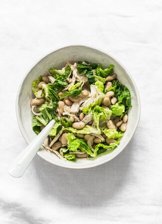 Warm salad with beans, baked chicken breast, romaine lettuce on a light background, top viewの写真素材