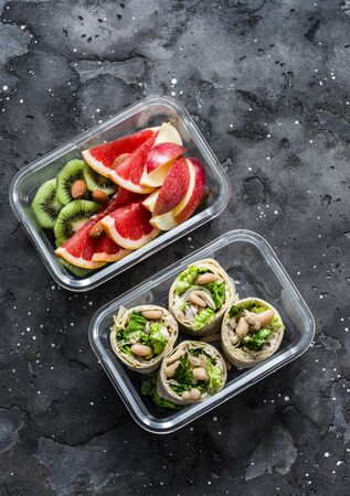 Healthy diet food lunch box - fruit and chicken, beans, green salad pita bread on a dark background, top view. Sweet b savory lunch boxの写真素材
