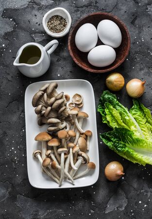 Ingredients for cooking healthy breakfast, brunch - egg, mixed mushrooms and green salad on a dark background, top viewの写真素材