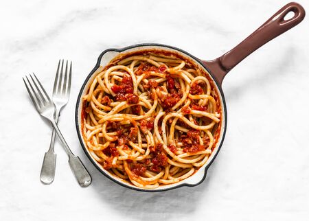 Traditional italian roman pasta - bucatini with amatricana tomato sauce in a cooking pan on a light background, top viewの写真素材