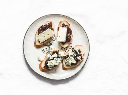 Plate with fig jam, gorgonzola and brie cheese bruschetta on a light background, top viewの写真素材