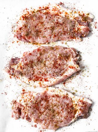 Raw pork chops with spices on a light background, top view. Ingredient foodの写真素材