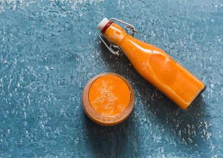 Glass and takeaway bottle with vitamin mango magic smoothies on a blue background, top view.  Smoothies with ripe mango, carrot, orange, honey, ginger. Detox healthy drinkの写真素材