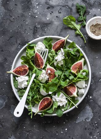 Figs, soft cheese, arugula salad on dark background, top view. Delicious breakfast, snack, appetizer, tapasの写真素材