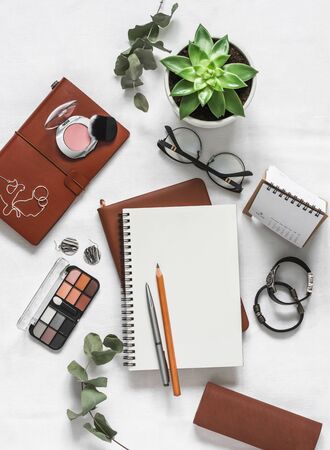 Women's background with notebooks, cosmetic, pens, flowers on a light table, top view. Flat lay beautiful female still lifeの写真素材