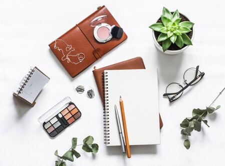 Women's table with notebooks, cosmetic, pens, succulent flower on a light table, top view. Flat lay...