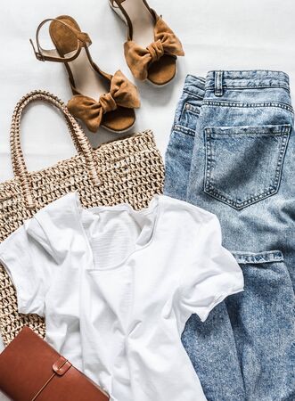Women's clothing summer - mom's jeans, suede brown wedge sandals, white cotton t-shirt, eco bag straw on a light background, top viewの写真素材
