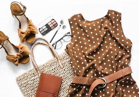 Polka dot summer brown dress, suede wedge sandals, eco straw tote bag, cosmetics on a light background, top view. Women's clothing setの写真素材