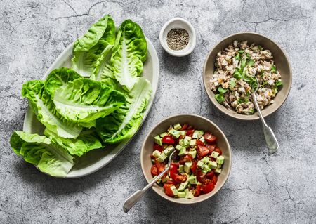 Ingredients for cooking - leaf of mini roman salad and tuna, egg, tomato, avocado salad on a gray background, top view. Delicious appetizer, tapas, snackの写真素材