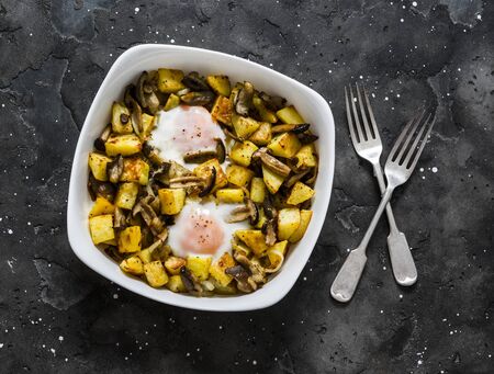 Baked potatoes with mushrooms and eggs - delicious lunch, breakfast, snack on a dark background, top viewの写真素材