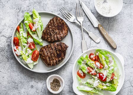 Beef medium rare steak and romaine salad cherry tomatoes yogurt dressing salad on a gray background, top viewの写真素材