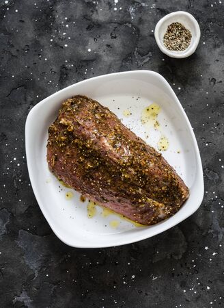 Raw marinated spices pork fillet in a baking dish on a dark background, top viewの写真素材