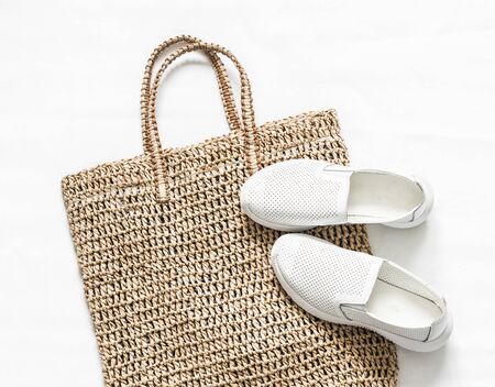 Eco bag made of straw, sport white snickers shoes on a white background, top view. Shopping walking conceptの写真素材