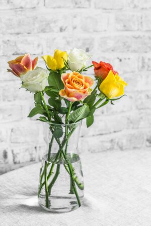 Bouquet of roses in a glasses vase on a table in a bright room. Cozy beautiful home interior conceptの写真素材