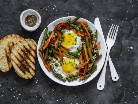 Eggs vegetable stir fry asian style shakshuka on a dark background, top view. Delicious healthy breakfast, lunchの写真素材