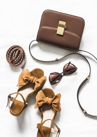 Cross body brown leather bag, suede wedge sandals and sunglasses on a light background, top view. Fashion conceptの写真素材