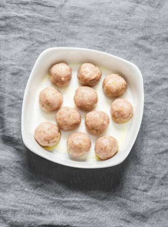 Raw chicken meatballs in a baking dish on a grey background, top view. Cooking baked meatballsの写真素材