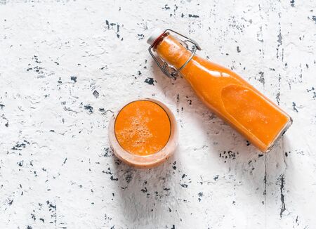 Glass and takeaway bottle with mango magic smoothies on a light background, top view.  Smoothies with ripe mango, carrot, orange, honey, ginger. Detox drinkの写真素材
