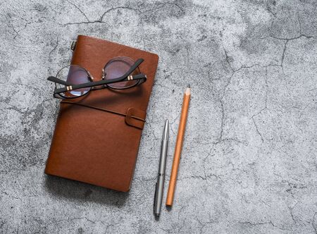 Leather personal organizer, pen, pencil, glasses  on a gray table, top view. Business conceptの写真素材