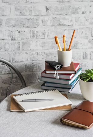 Home online school education. Stack of books , notebooks, pens, pencils, notepad, phone on the table in a bright roomの写真素材