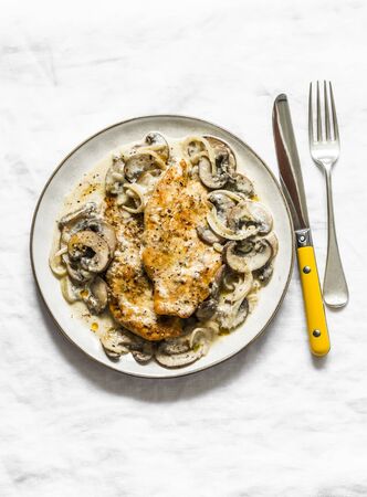 Fried chicken fillet with cheesy mushrooms cream sauce on a light background, top view. Delicious homemade lunchの写真素材