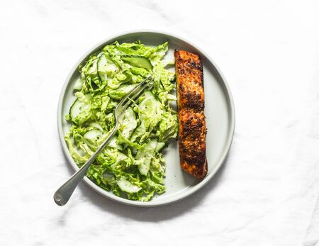 Baked salmon and savoy cabbage, cucumber salad on light background, top view. Healthy diet foodの写真素材