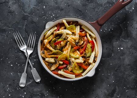 Pasta, zucchini, mushrooms, sweet paprika vegetable stewed tomato sauce in a pan on a dark background, top view. Vegetarian foodの写真素材