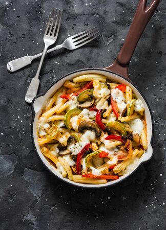 Baked mozzarella pasta with zucchini, mushrooms, sweet paprika vegetable stewed tomato sauce in a pan on a dark background, top view. Vegetarian foodの写真素材