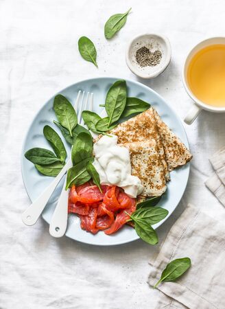 Delicious breakfast - crepes with smoked salmon, spinach, cream fresh on a light background, top viewの写真素材