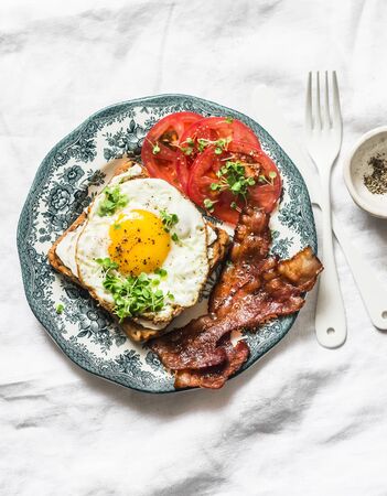 Nutritious breakfast - fried egg toast, bacon and tomatoes on a light background, top viewの写真素材