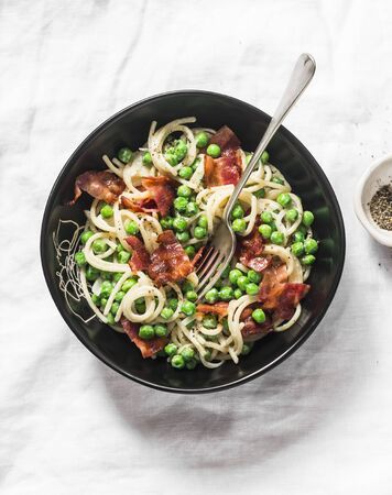 Spaghetti with crispy ham and creamy green peas on a light background, top viewの写真素材