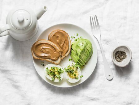 Peanut butter sandwiches, boiled egg with micro greens, avocado - healthy breakfast or snack on a light background, top viewの写真素材