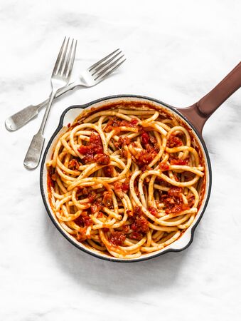 Traditional italian roman pasta - bucatini with amatricana tomato sauce in a cooking pan on a light background, top viewの写真素材