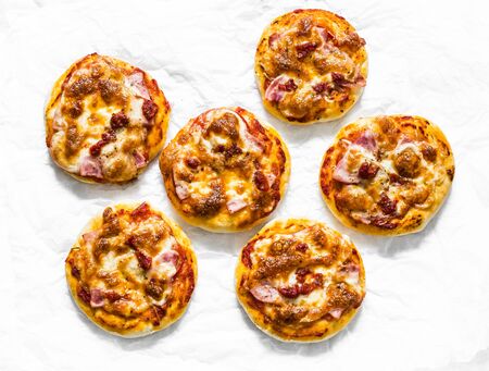 Mini ham, tomato sauce, mozzarella pizza on a light background, top view. Delicious breakfast, snack, tapasの写真素材