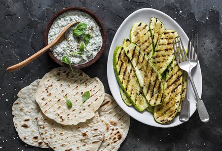 Grilled zucchini, tortillas and tzadziki sauce - delicious greek style snack, tapas on a dark background, top viewの写真素材