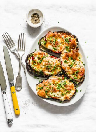 Roasted eggplant with ham, tomatoes and mozzarella - delicious appetizer, tapas on a light background, top viewの写真素材