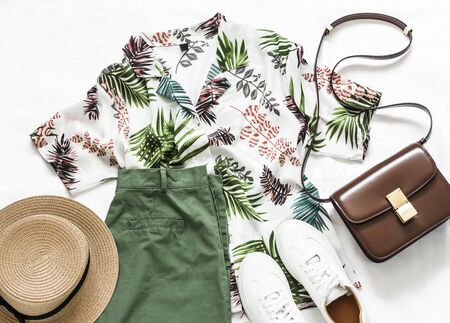 Summer travel, vacation, walking women's clothing - shirt plant print short sleeve, bermuda shorts, sneakers, bag and hat on a light background, top viewの写真素材